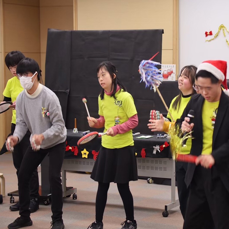 イベント活動でタンバリンなど楽器を演奏するダウン症の子どもたち